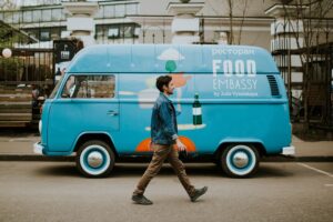 Man walks past a blue van with "Food Embassy" logo